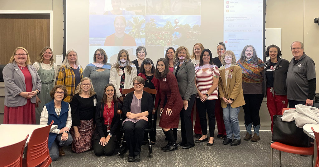 Dr. Marsha Hughes-Gay sits in a rocking chair while posing for a photo with colleagues during a retirement party held in her honor