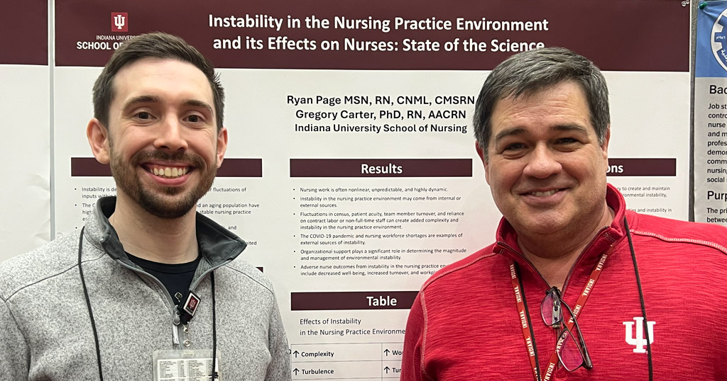 Ryan Page, a PhD student, and Dr. Greg Carter pose for a photo by a poster during the Midwest Nursing Research Society 49th Annual Research Conference in Indianapolis.