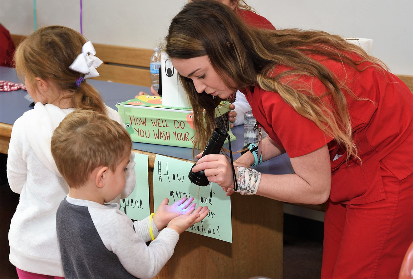 Child sees germs on hands under black light at Science Fest